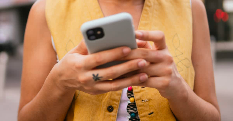 Woman wearing a yellow vest with cell phone in her hands